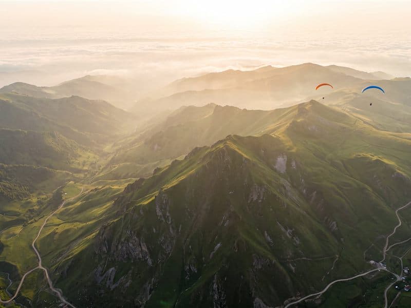 Paragliders soaring above the green ridges of the Greater Caucasus