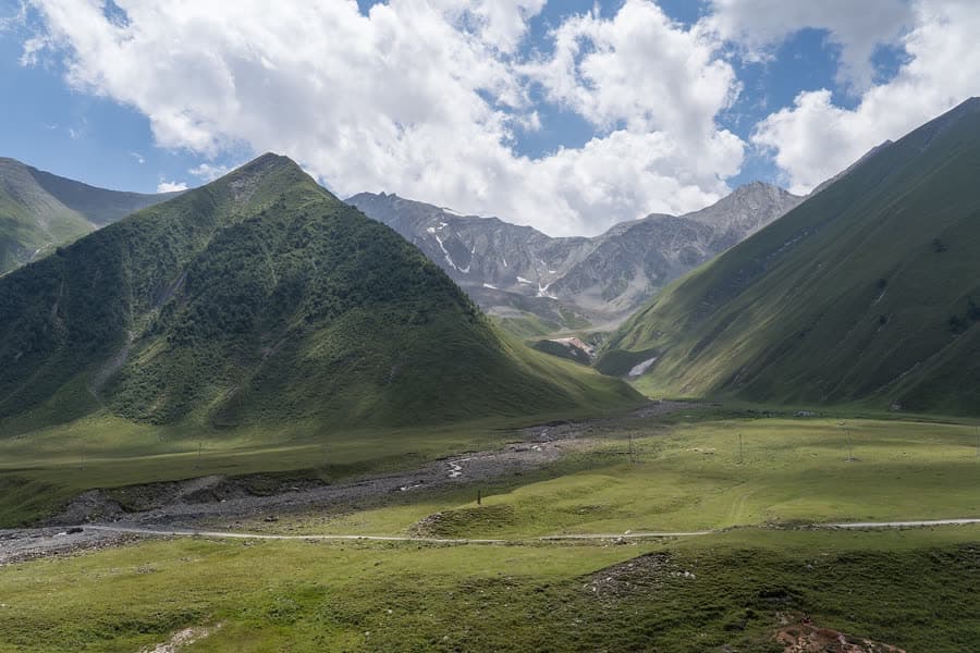 The wide green glacial floor of the Truso Valley beneath high Caucasus ridges